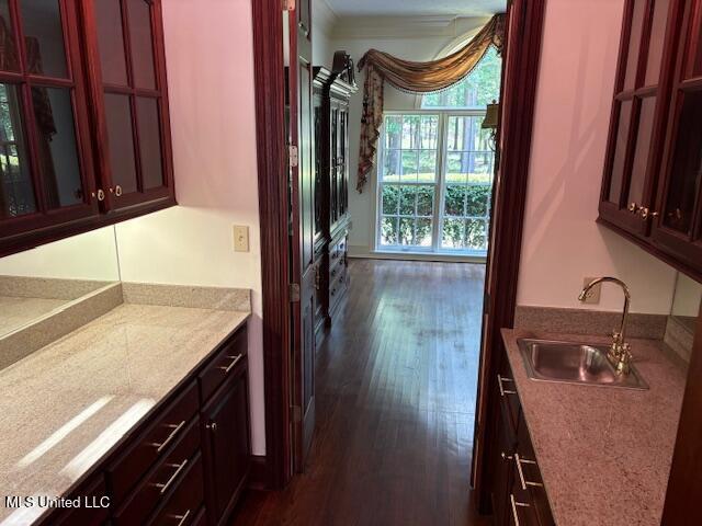 kitchen with light countertops, dark wood finished floors, a sink, and reddish brown cabinets