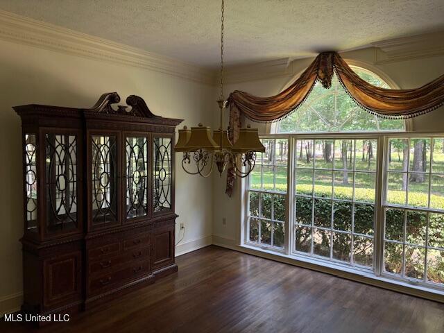 unfurnished dining area with dark wood-style flooring, a textured ceiling, a chandelier, and baseboards