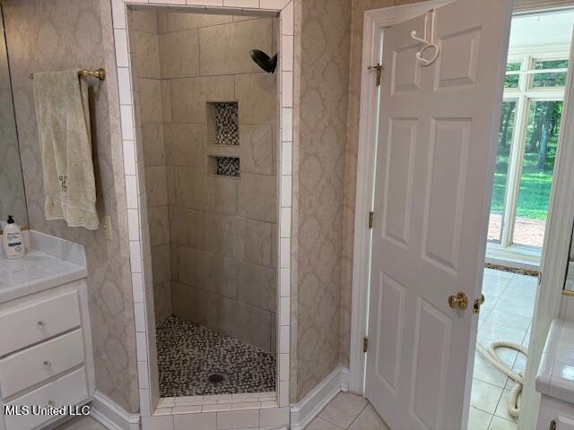 bathroom with vanity, a walk in shower, and a healthy amount of sunlight