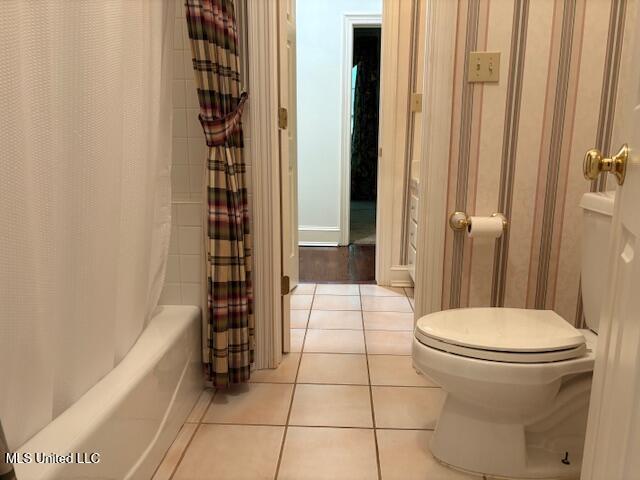 full bath with toilet, shower / bathtub combination with curtain, and tile patterned flooring