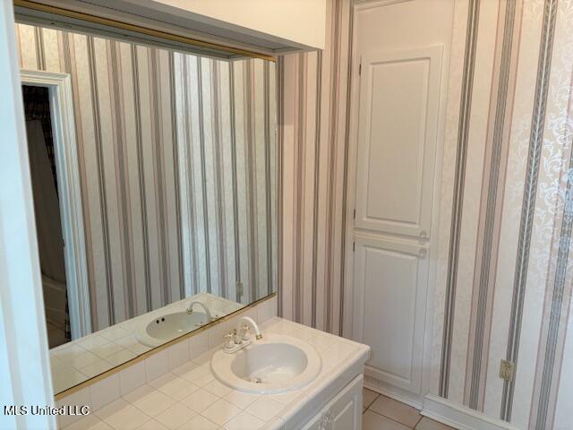 bathroom with vanity, tile patterned flooring, and wallpapered walls