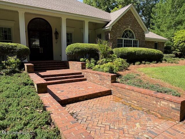 view of exterior entry featuring roof with shingles