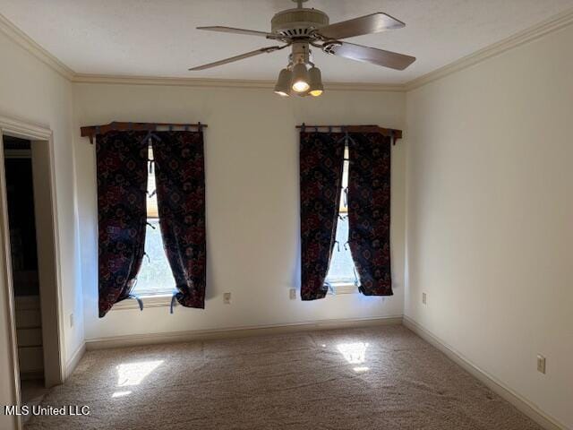 carpeted empty room with crown molding, baseboards, and ceiling fan