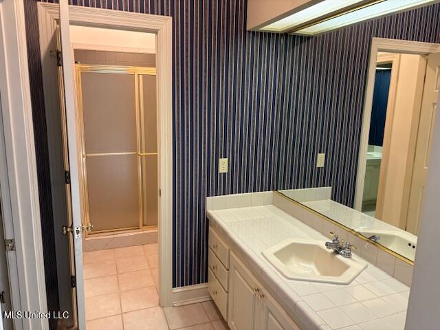 full bathroom with vanity, wallpapered walls, tile patterned flooring, and a stall shower