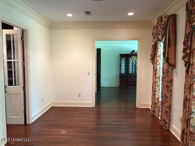 unfurnished room with baseboards, visible vents, ornamental molding, and dark wood-type flooring