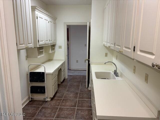 laundry room with dark tile patterned flooring and a sink