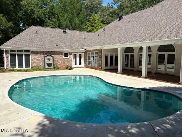 outdoor pool with french doors and a patio