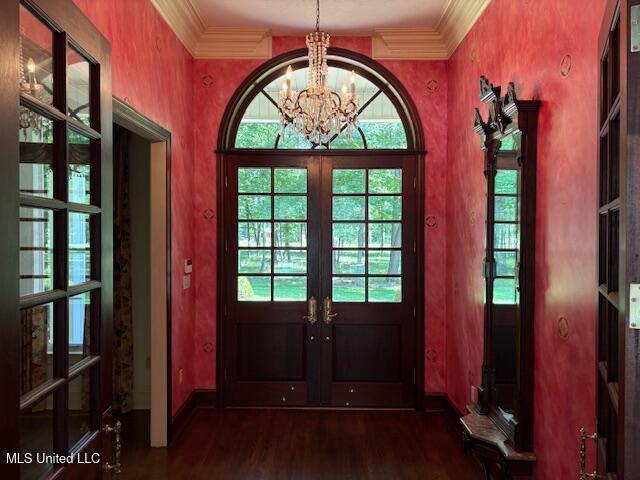 doorway featuring french doors, wood finished floors, baseboards, a chandelier, and ornamental molding