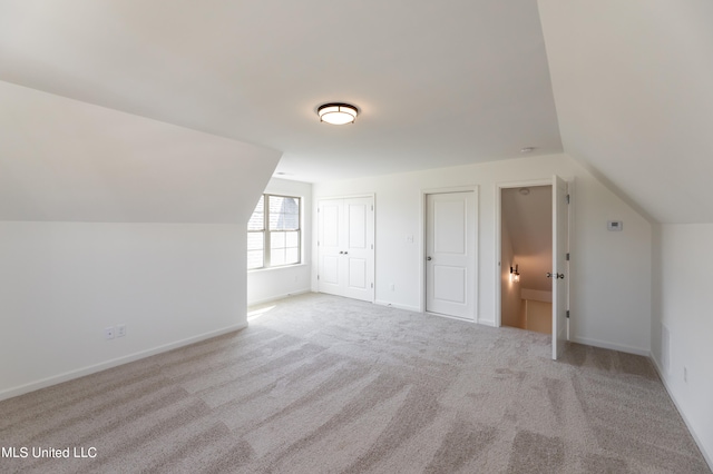 bonus room with light carpet and vaulted ceiling