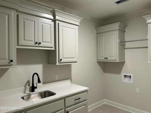 laundry room with hookup for a washing machine, baseboards, cabinet space, a sink, and crown molding