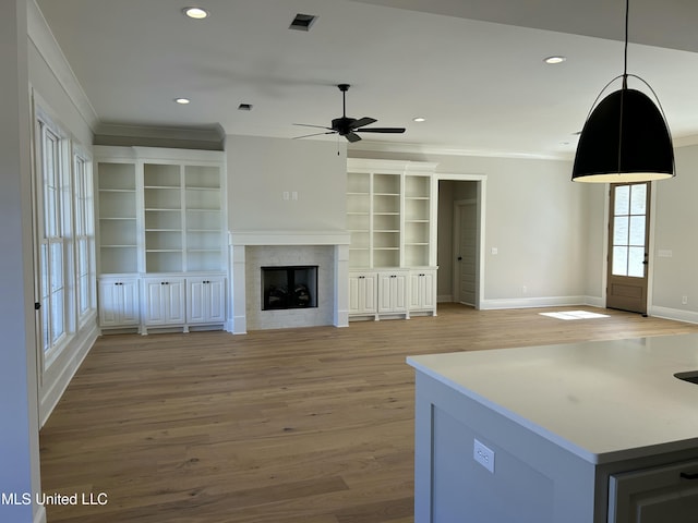 unfurnished living room featuring a fireplace, visible vents, light wood finished floors, and ornamental molding