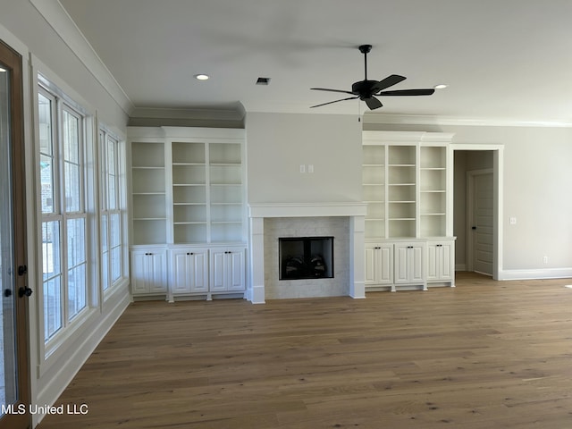 unfurnished living room featuring wood finished floors, recessed lighting, a fireplace, crown molding, and baseboards