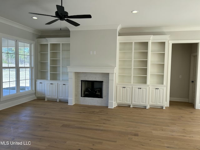 unfurnished living room with recessed lighting, wood finished floors, ornamental molding, and a tile fireplace