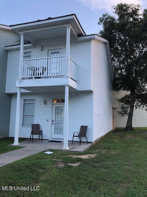 back of house with a lawn and a balcony