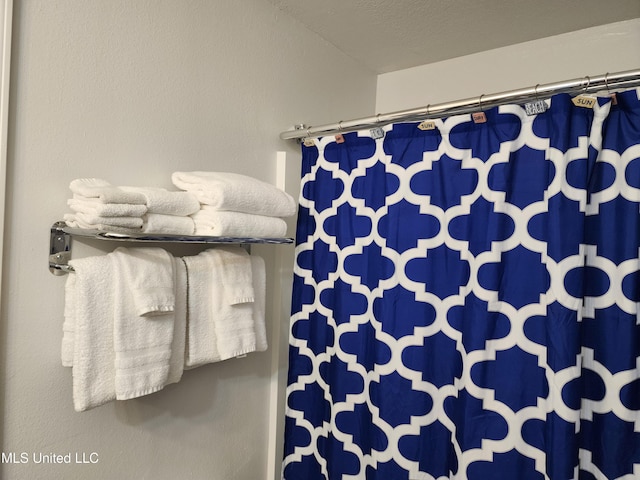 bathroom with a shower with shower curtain and a textured ceiling