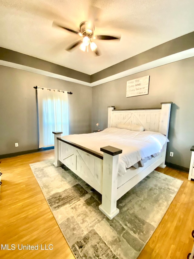 bedroom featuring ceiling fan, wood-type flooring, and a textured ceiling