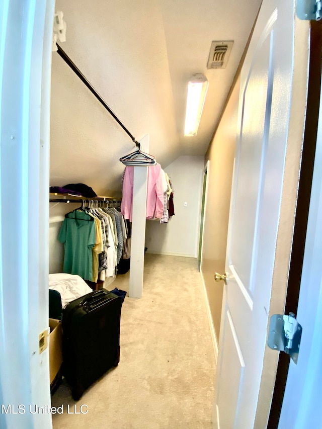 walk in closet featuring vaulted ceiling and light colored carpet