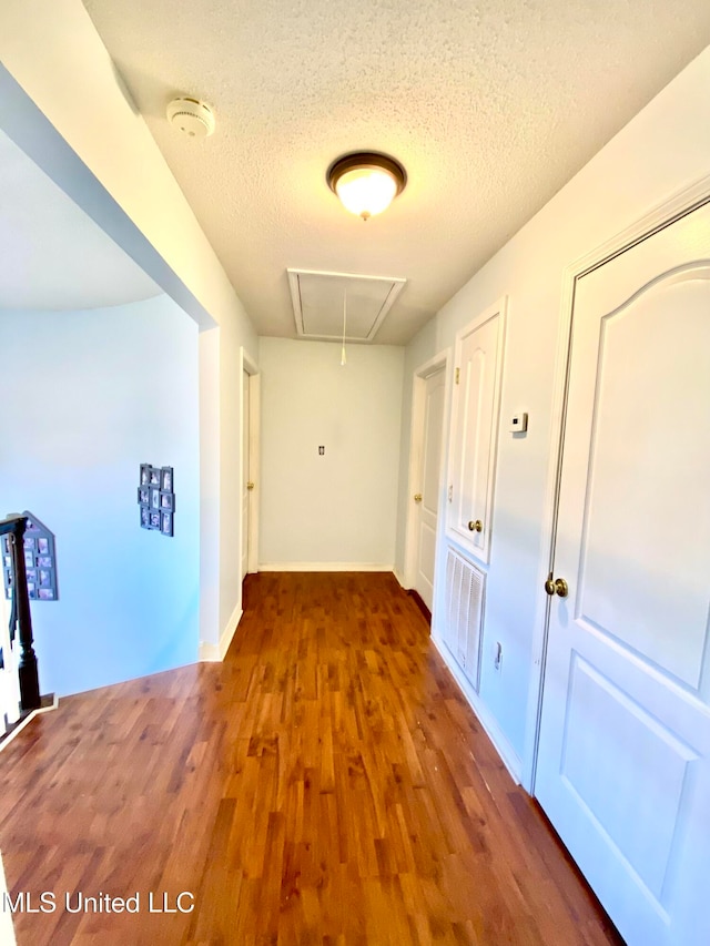 hallway with dark hardwood / wood-style floors and a textured ceiling