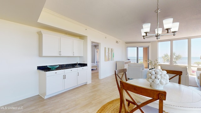 dining space featuring light hardwood / wood-style flooring, a chandelier, sink, and crown molding