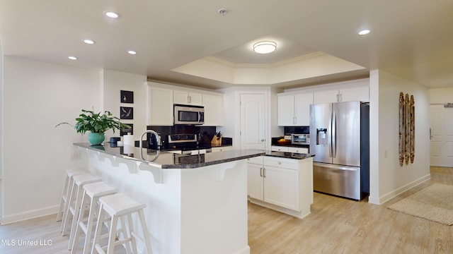 kitchen with decorative backsplash, dark stone counters, ornamental molding, white cabinetry, and appliances with stainless steel finishes