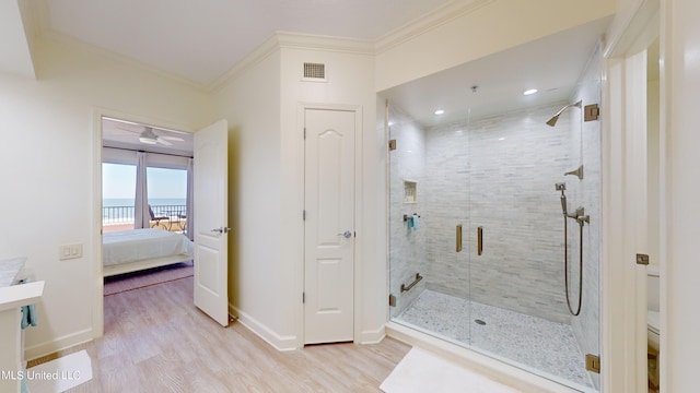 bathroom featuring a shower with door, crown molding, wood-type flooring, and a water view