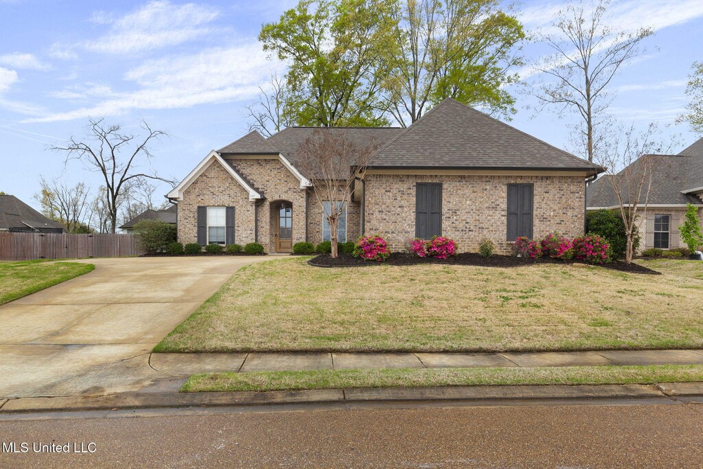105 Federal Cv, Madison, MS 39110 - french country home featuring driveway, brick siding, fence, and a front lawn