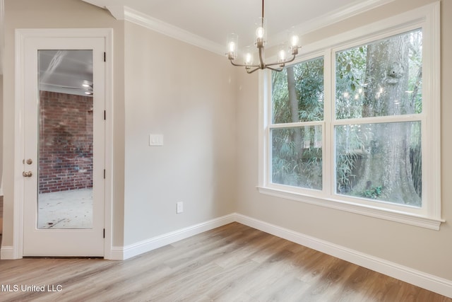 unfurnished dining area featuring a notable chandelier, ornamental molding, light hardwood / wood-style flooring, and a wealth of natural light