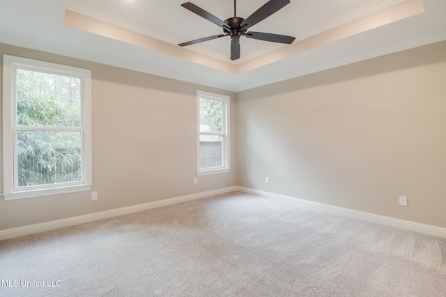 unfurnished room featuring a raised ceiling, ornamental molding, carpet flooring, and ceiling fan