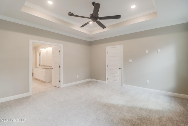 unfurnished bedroom featuring crown molding, light colored carpet, ensuite bathroom, and a tray ceiling