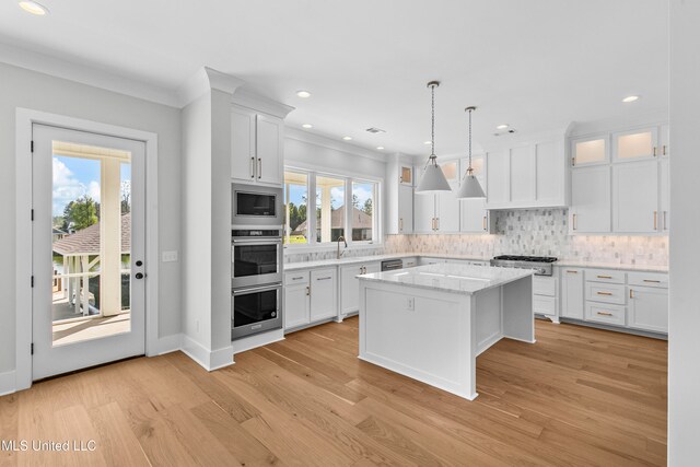 kitchen with pendant lighting, white cabinets, light wood-type flooring, and a kitchen island