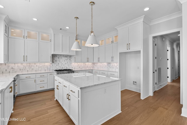 kitchen featuring light stone countertops, a kitchen island, white cabinetry, and light hardwood / wood-style floors