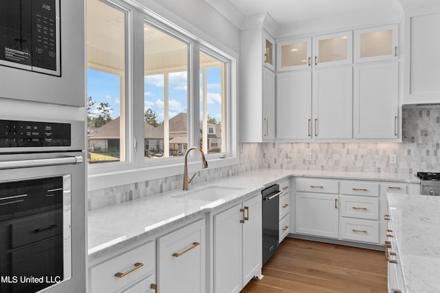 kitchen featuring hardwood / wood-style floors, sink, white cabinets, appliances with stainless steel finishes, and light stone counters