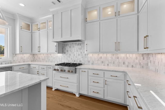 kitchen featuring light hardwood / wood-style flooring, light stone countertops, stainless steel gas stovetop, white cabinets, and tasteful backsplash