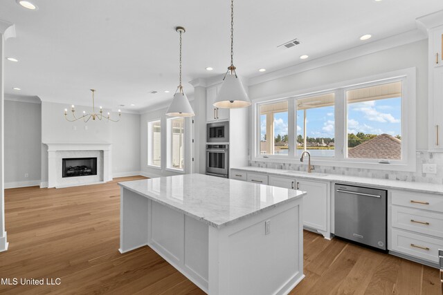 kitchen featuring a kitchen island, stainless steel appliances, white cabinets, light hardwood / wood-style floors, and tasteful backsplash