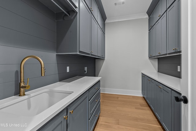 washroom with ornamental molding, sink, and light wood-type flooring