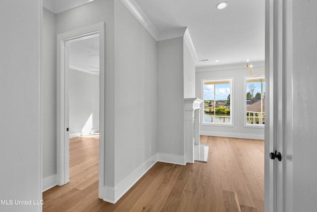 hall featuring ornamental molding, a chandelier, and light wood-type flooring