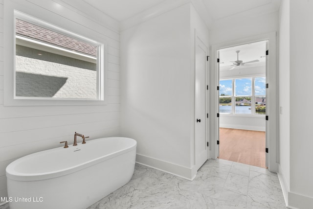 bathroom featuring a bathing tub, ornamental molding, wooden walls, and ceiling fan