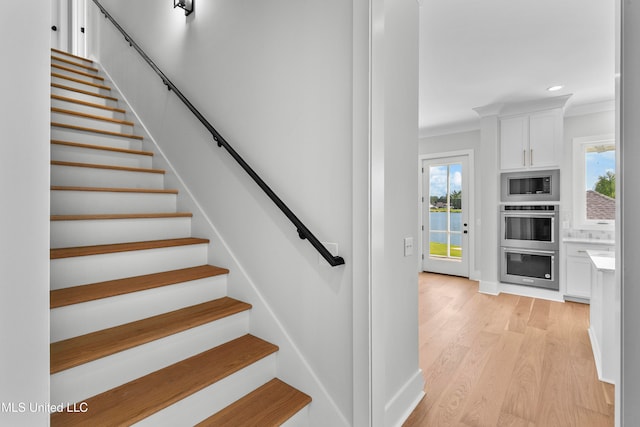 staircase with ornamental molding and hardwood / wood-style floors