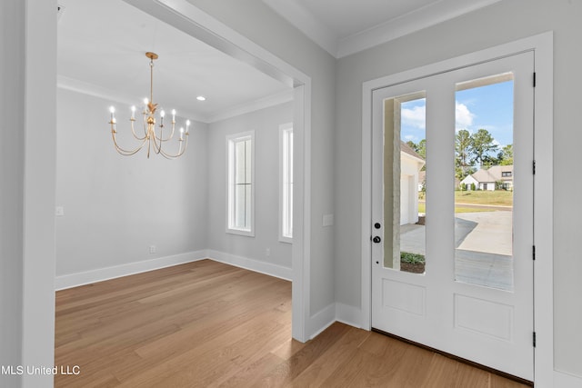 foyer entrance with light hardwood / wood-style floors, crown molding, and a chandelier