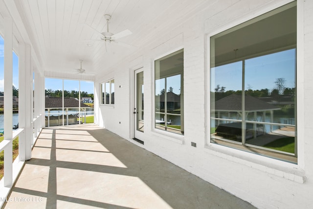 sunroom with a healthy amount of sunlight, a water view, and ceiling fan