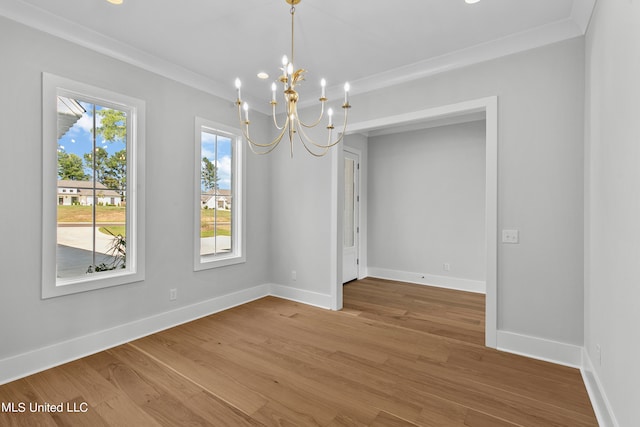 unfurnished dining area featuring ornamental molding, hardwood / wood-style floors, and a notable chandelier