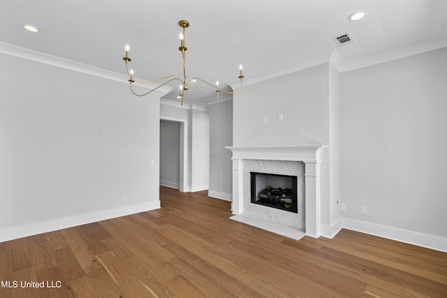 unfurnished living room featuring crown molding, a notable chandelier, and wood-type flooring