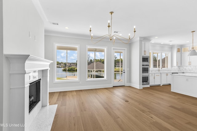 126 Herons Bay Cir Lot 1136, Madison, MS 39110 - unfurnished living room featuring light wood finished floors, baseboards, visible vents, and an inviting chandelier