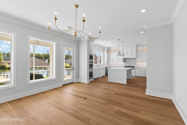 kitchen featuring hanging light fixtures, stainless steel appliances, a center island, light wood-type flooring, and white cabinetry