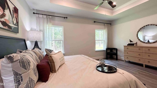 bedroom featuring ornamental molding, hardwood / wood-style floors, ceiling fan, and a tray ceiling