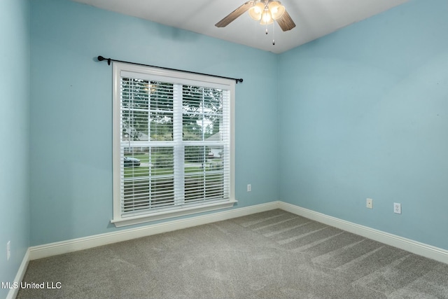 carpeted spare room featuring a ceiling fan and baseboards