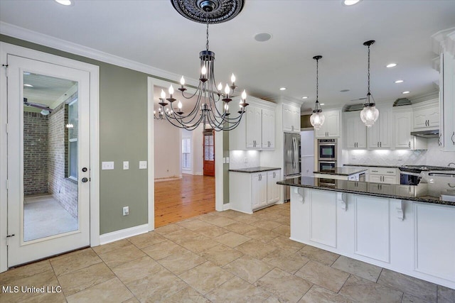 306 Canebreak Cv, Madison, MS 39110 - kitchen featuring stainless steel appliances, under cabinet range hood, white cabinets, tasteful backsplash, and crown molding