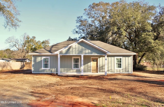 view of front of property with roof with shingles, fence, and board and batten siding