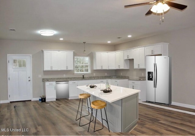 kitchen with a center island, white cabinetry, light countertops, dark wood-style floors, and appliances with stainless steel finishes