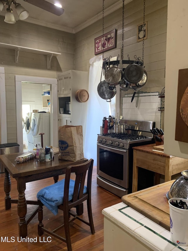 kitchen featuring dark hardwood / wood-style floors, backsplash, crown molding, independent washer and dryer, and stainless steel gas range oven